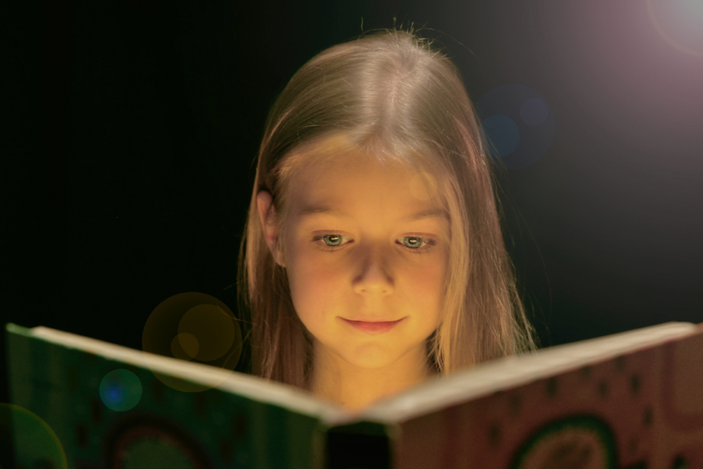 girl reading a book in the dark